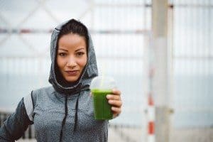 Successful urban sporty woman taking a rest for drinking nutritive detox smoothie. Fitness nutrition and healthy lifestyle concept.